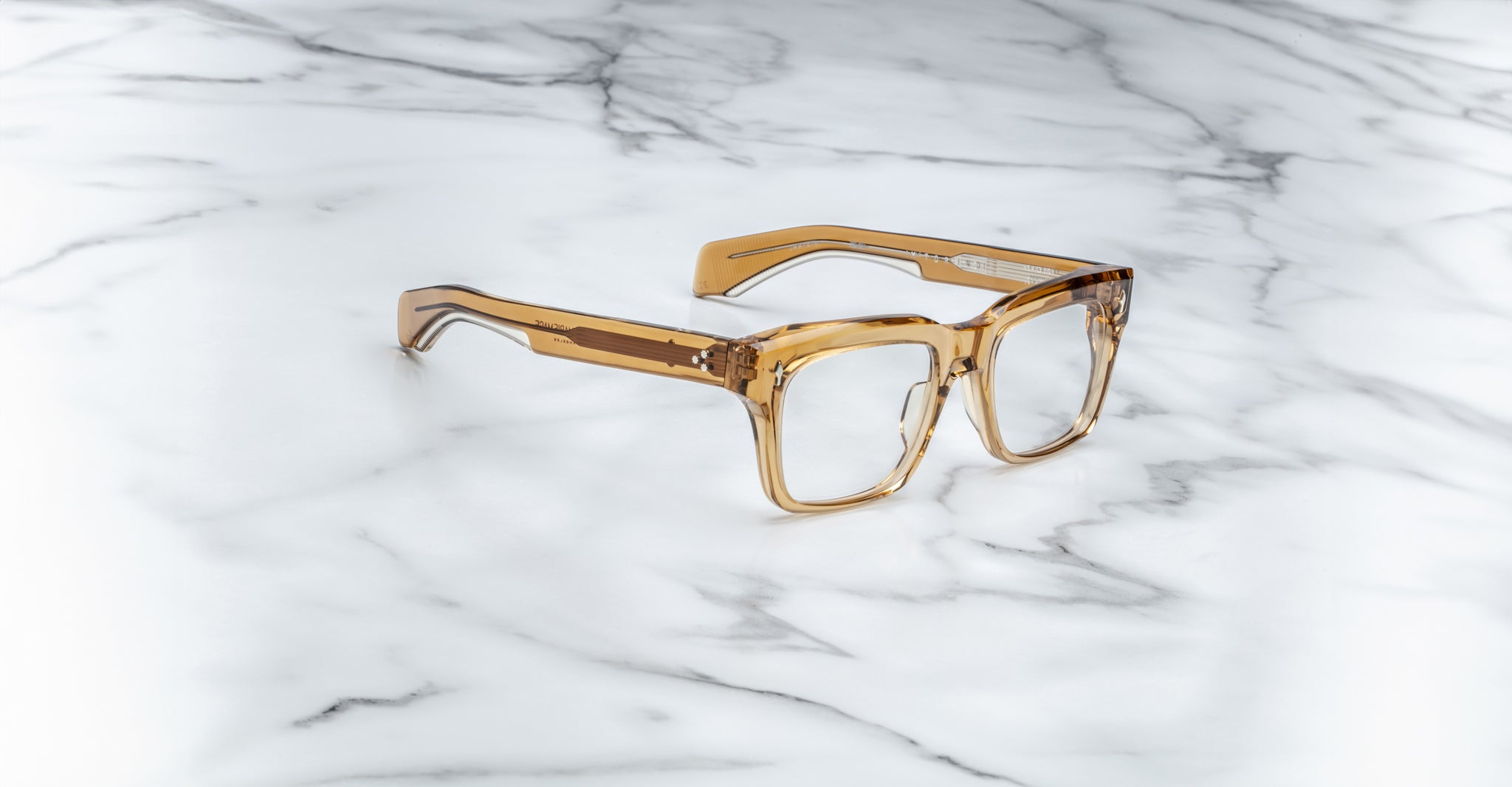 The Jacques Marie Mage Torino, bold rectangular eyeglass frames by Jacques Marie Mage, are crafted from translucent brown handcrafted acetate and displayed on a white marble surface.