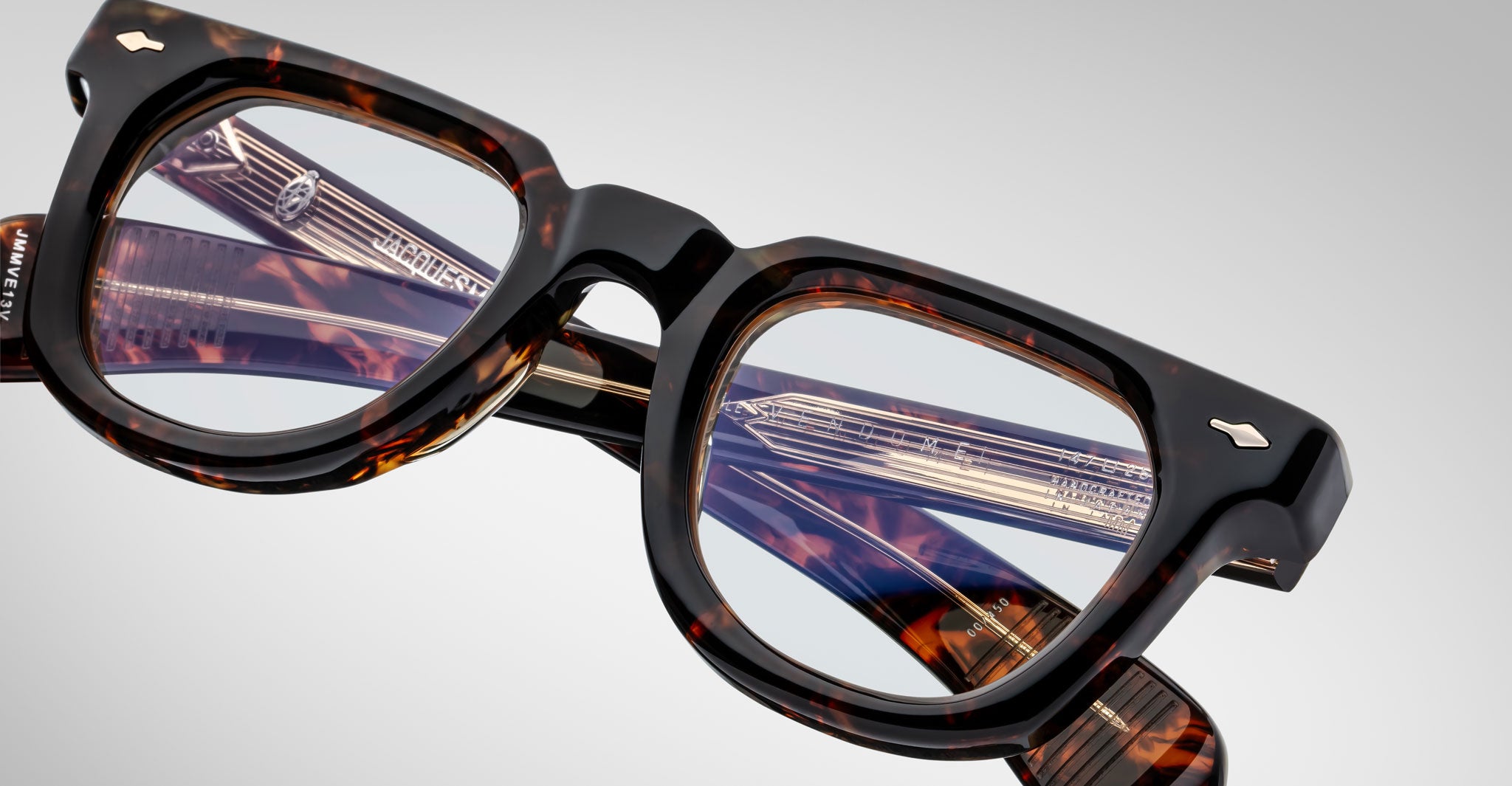 Close-up of Jacques Marie Mage Vendome optical frames, handcrafted in Japan with a tortoiseshell rectangular design and brand markings on the frame and temples, set against a plain light background.