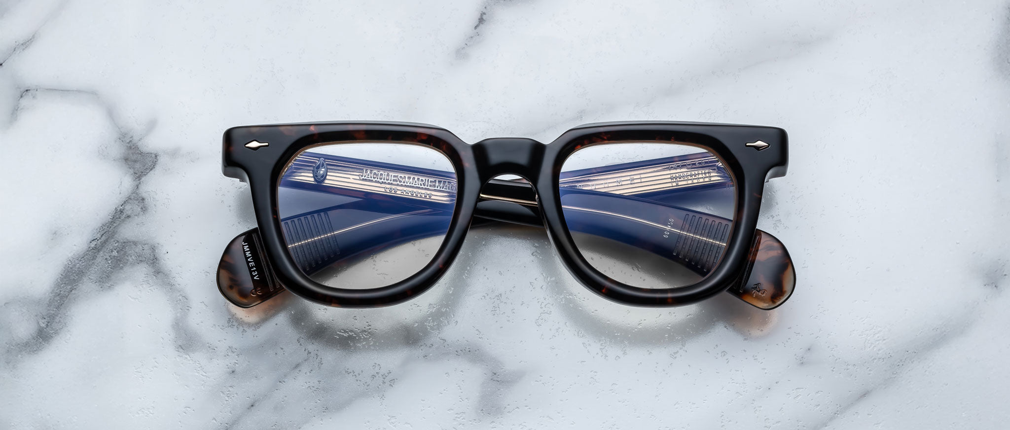 Jacques Marie Mage Vendome black-framed eyeglasses with blue and white reflections, shown from above.