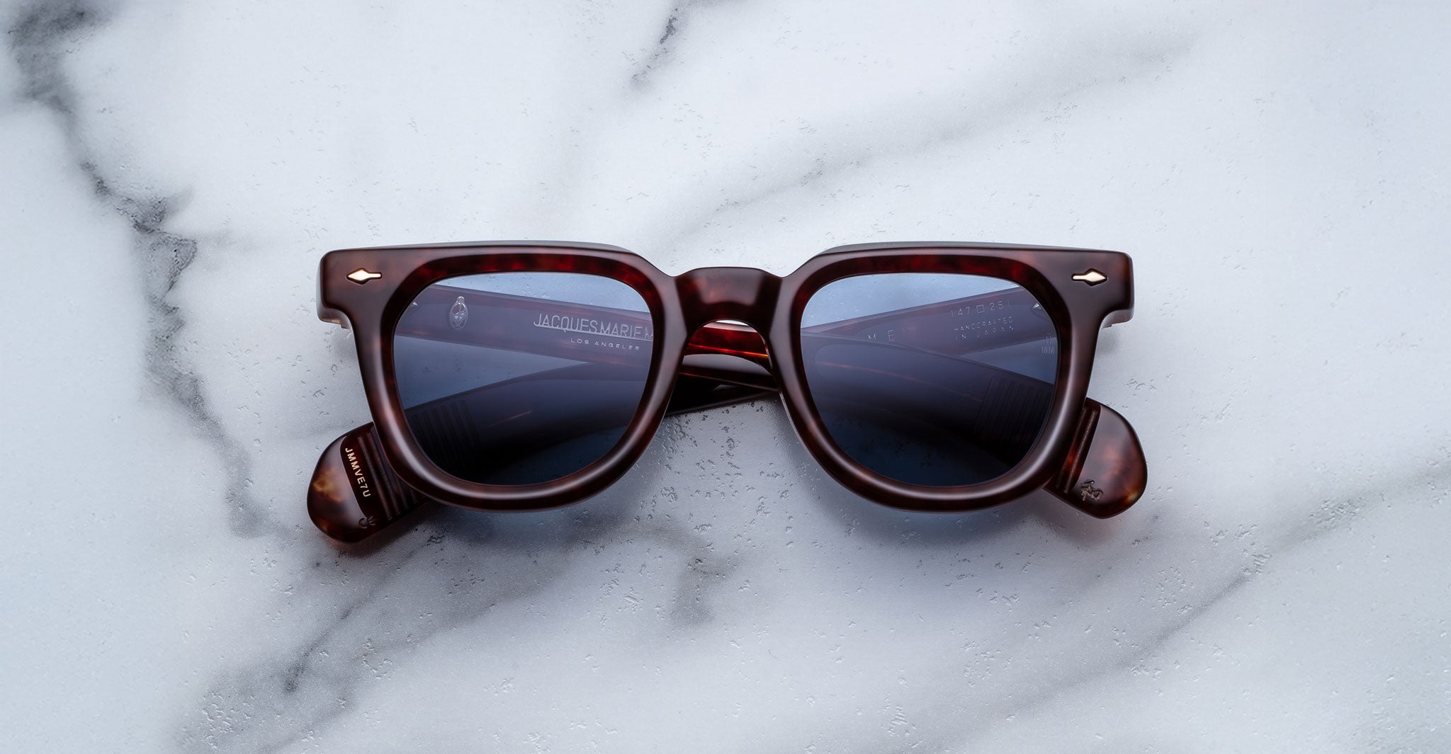 Jacques Marie Mage Vendome sunglasses by Jacques Marie Mage, featuring brown tortoiseshell square frames and dark lenses, handcrafted in Japan, displayed on a white marble surface.