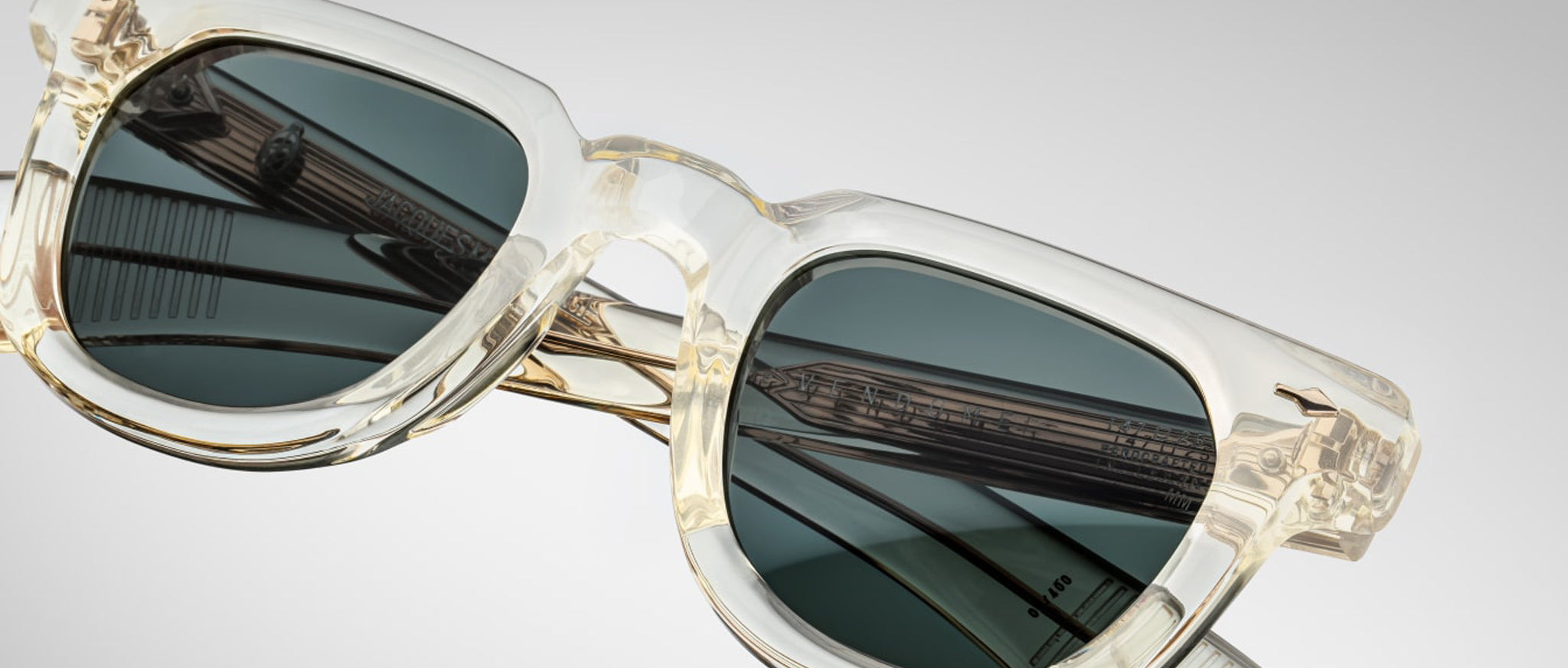 Close-up view of Jacques Marie Mage Vendome sunglasses with clear acetate frames and dark lenses, highlighting reflective details.
