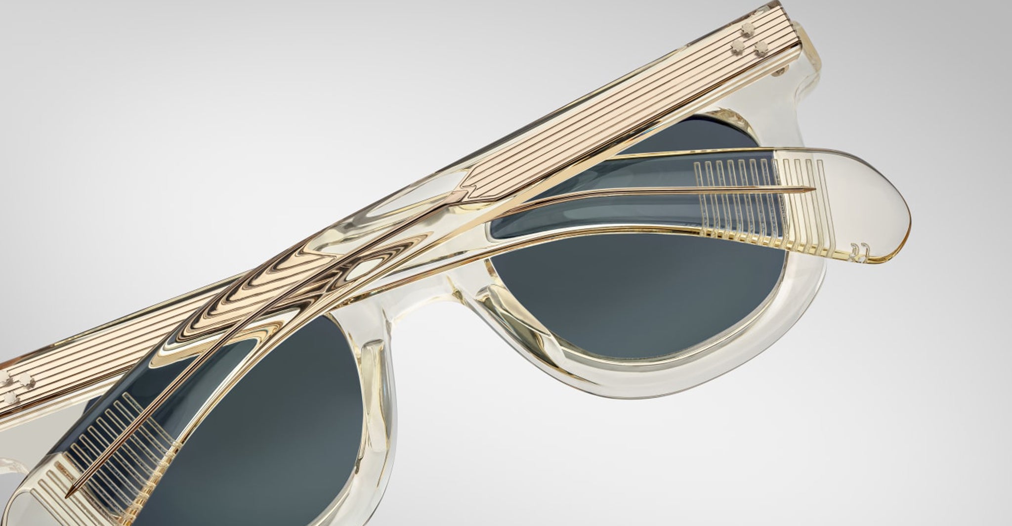 Partially folded Jacques Marie Mage Vendome sunglasses with translucent frames and dark lenses are displayed against a plain light background.