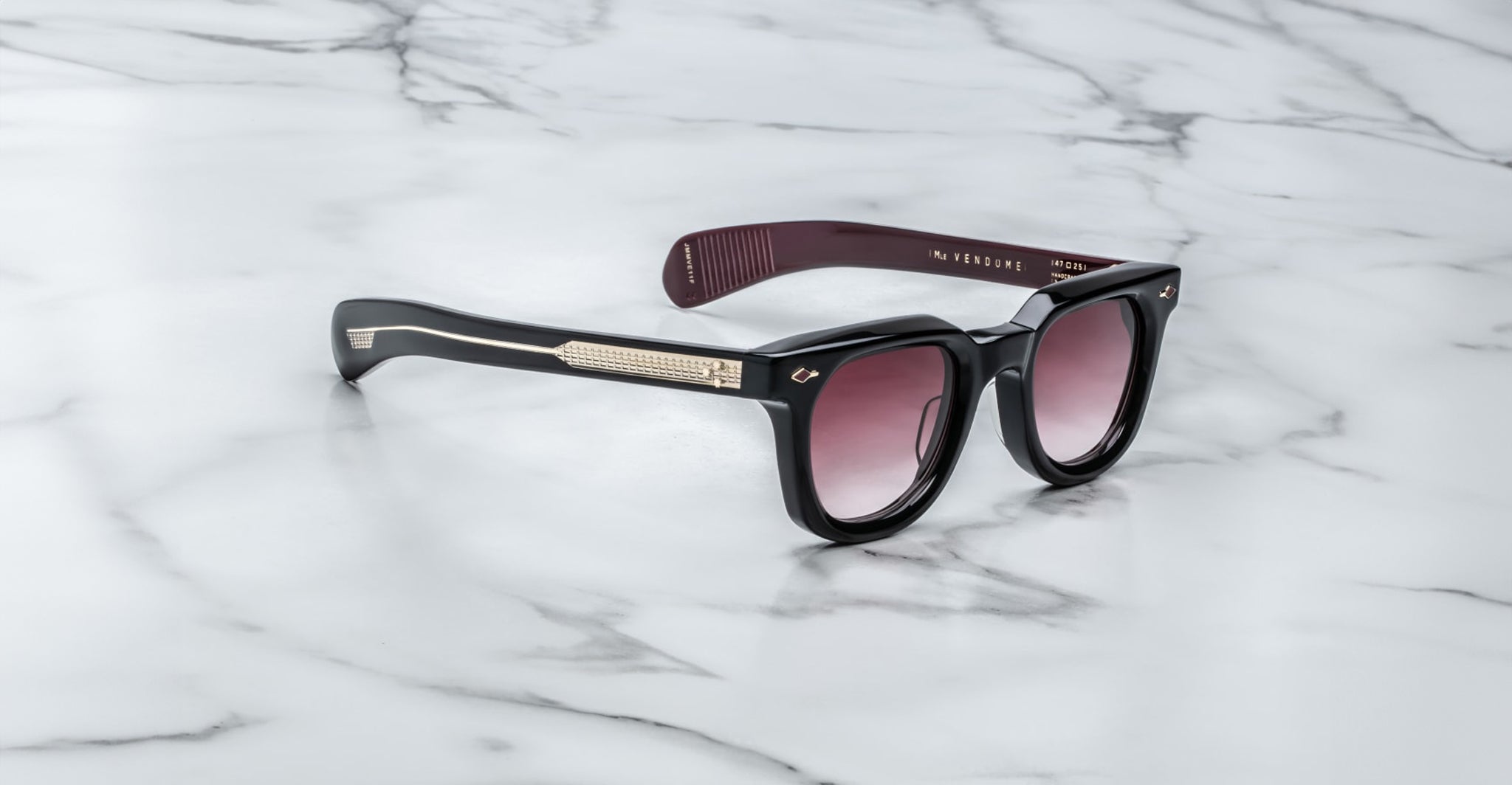 Jacques Marie Mage Vendome sunglasses, handcrafted in Japan with gradient lenses and gold-accented arms, are displayed on a white marble surface.