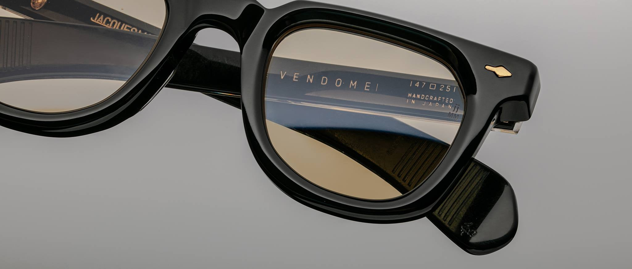 Close-up of Jacques Marie Mage Vendome black eyeglasses with brown lenses and visible branded markings inside the arm.