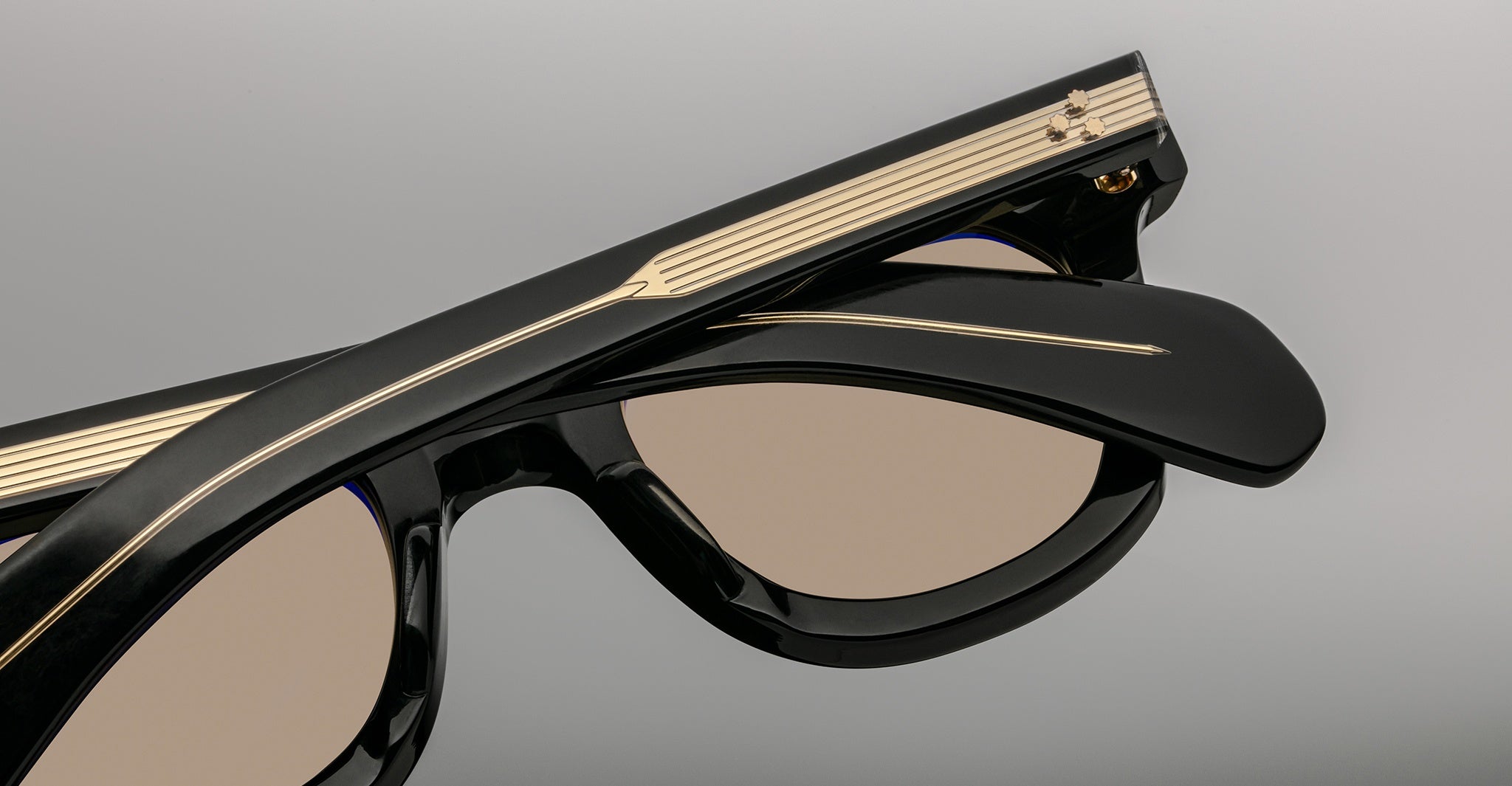 Close-up of Jacques Marie Mage Vendome sunglasses in black with gold temple accents and beige-tinted lenses, expertly handcrafted in Japan by Jacques Marie Mage, set against a neutral backdrop.