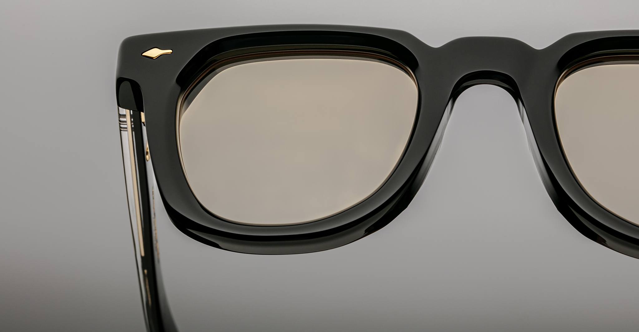 Close-up of Jacques Marie Mage Vendome eyeglasses by Jacques Marie Mage, handcrafted in Japan with black rectangular frames and gold accents, highlighting the left lens and temple against a neutral background.