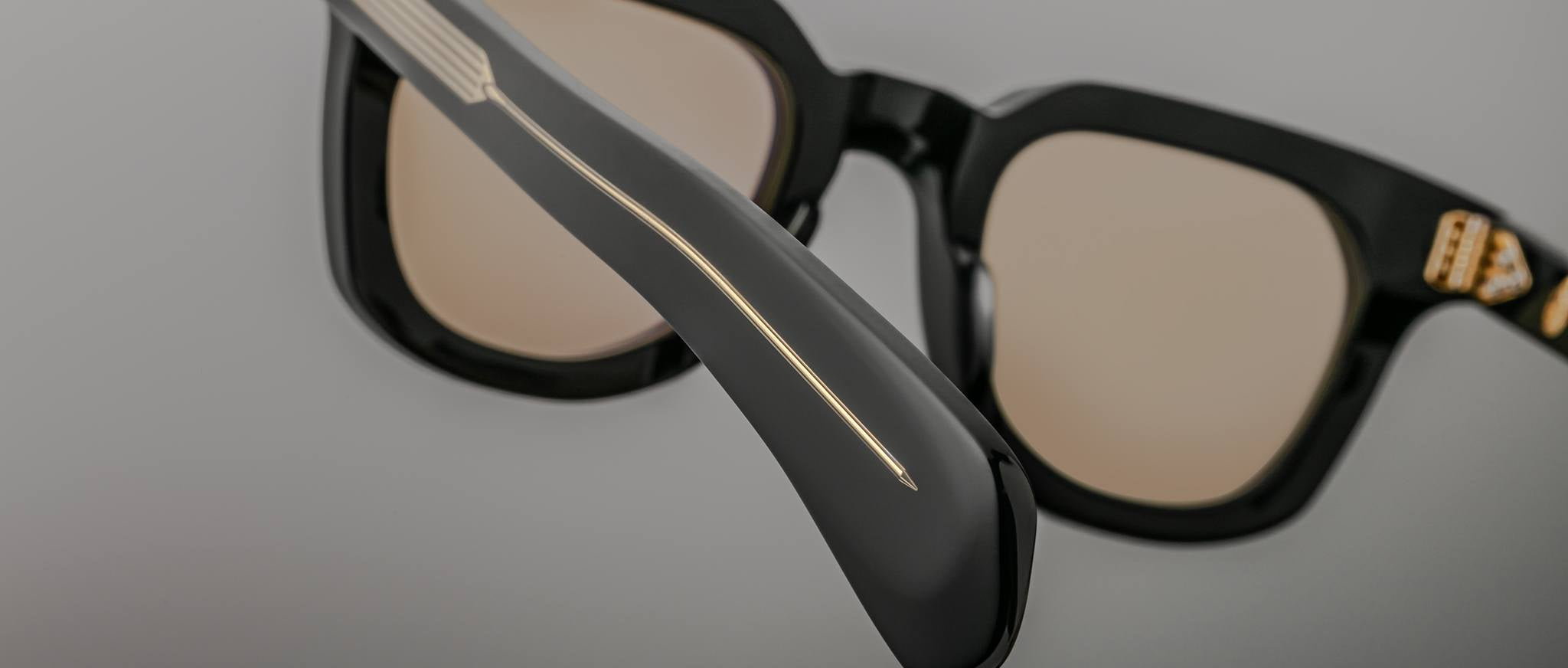 Close-up of Jacques Marie Mage Vendome black sunglasses, showing gold temple detailing and the brands signature gold emblem on frame.