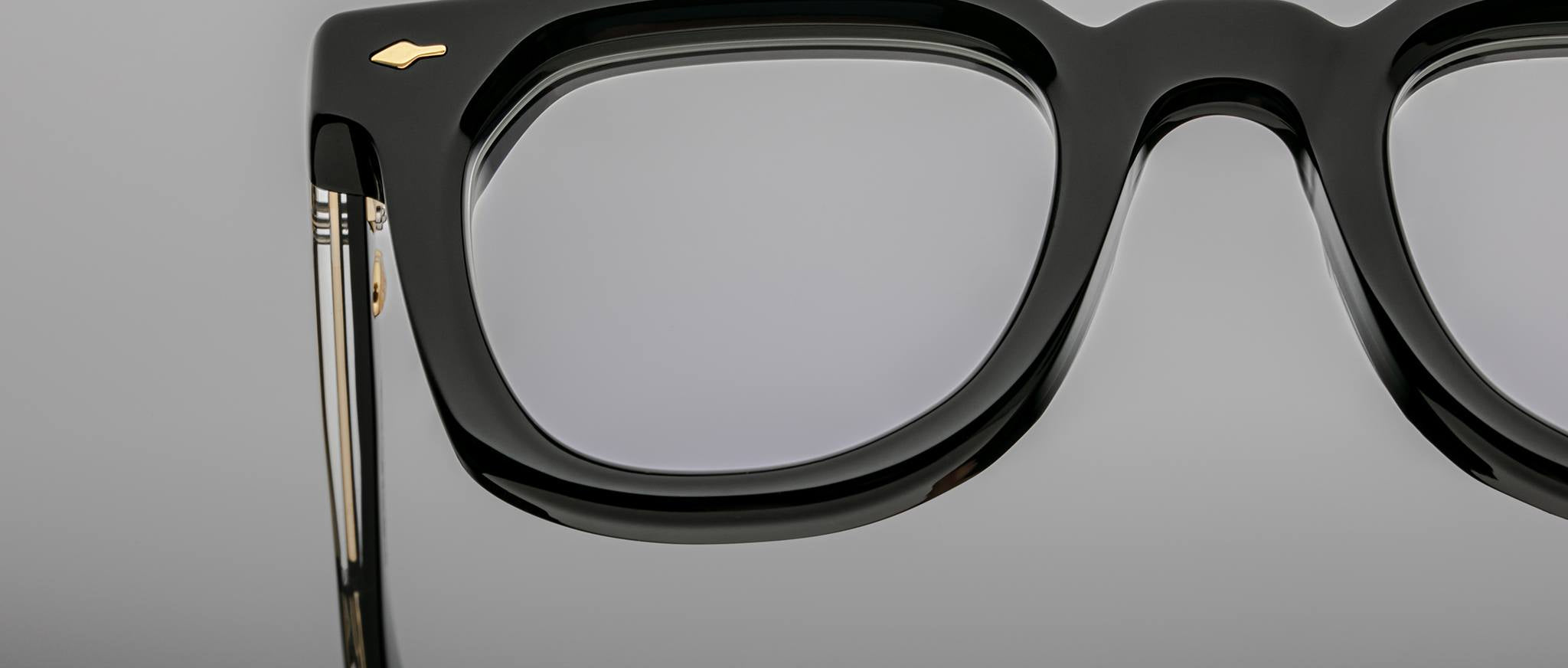 Close-up of Jacques Marie Mage Vendome eyeglasses, black frames with gold accents, logo visible, showing detailed metal temples.