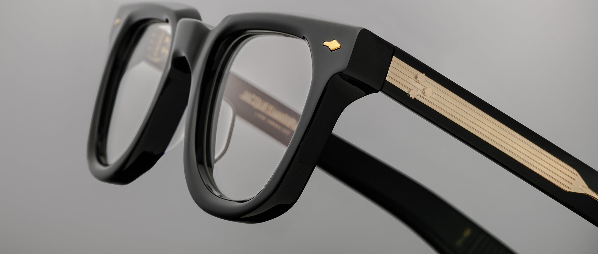 Close-up of Jacques Marie Mage Vendome black eyeglasses showing gold accents on the arms, front angle view.