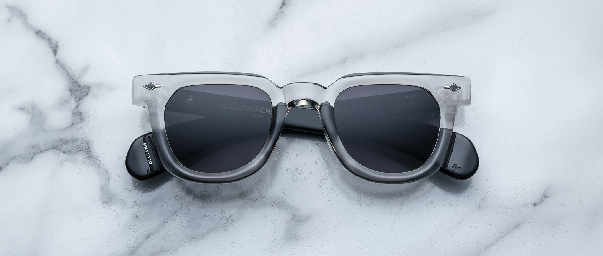 Jacques Marie Mage Vendome sunglasses with clear frames and dark lenses, top view.