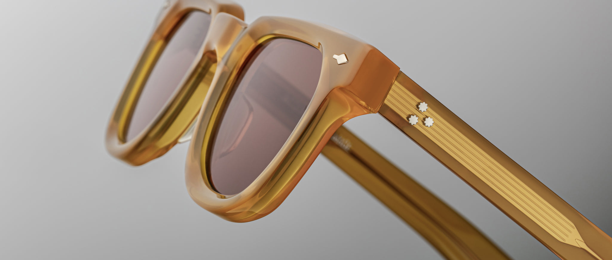 Close-up of Jacques Marie Mage Vendome sunglasses in amber with tinted lenses and retro metallic accents, viewed from the front.