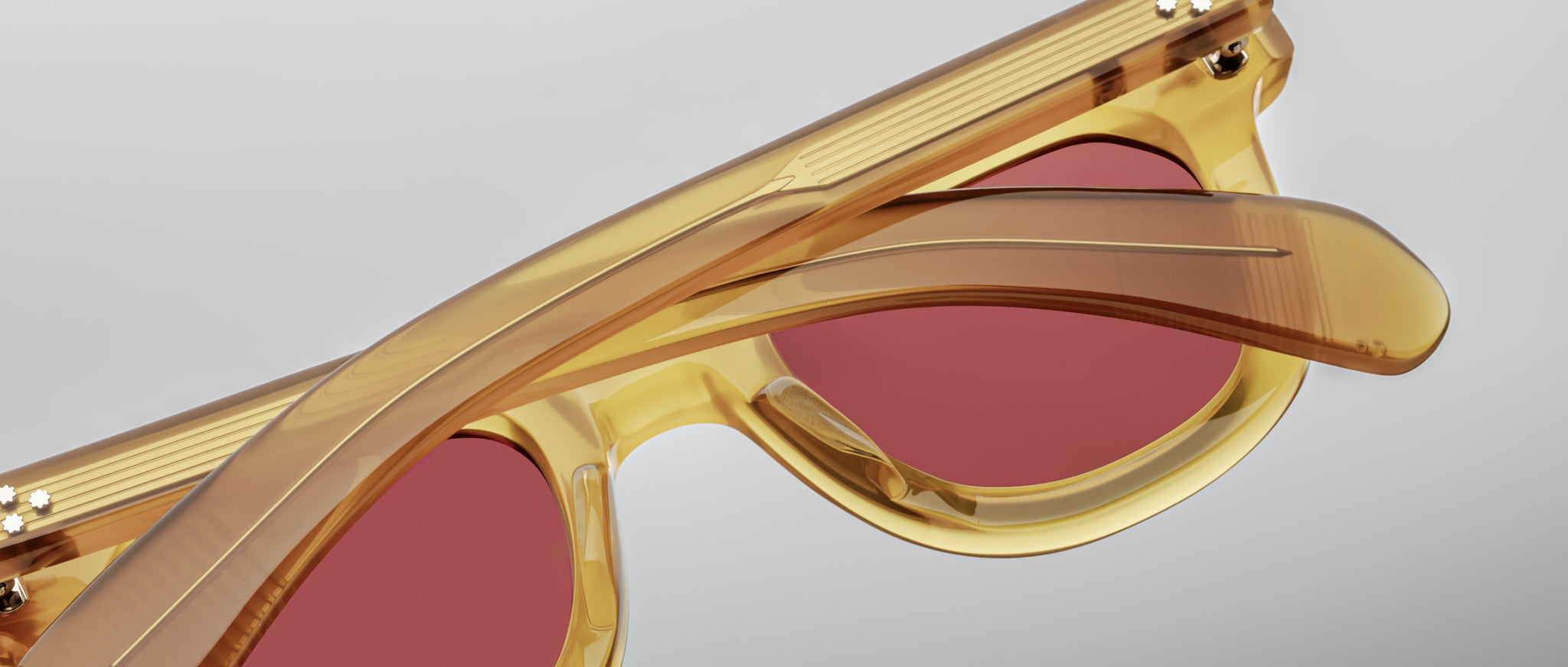Close-up of Jacques Marie Mage Vendome sunglasses, featuring yellow frames and red lenses, viewed from the front.