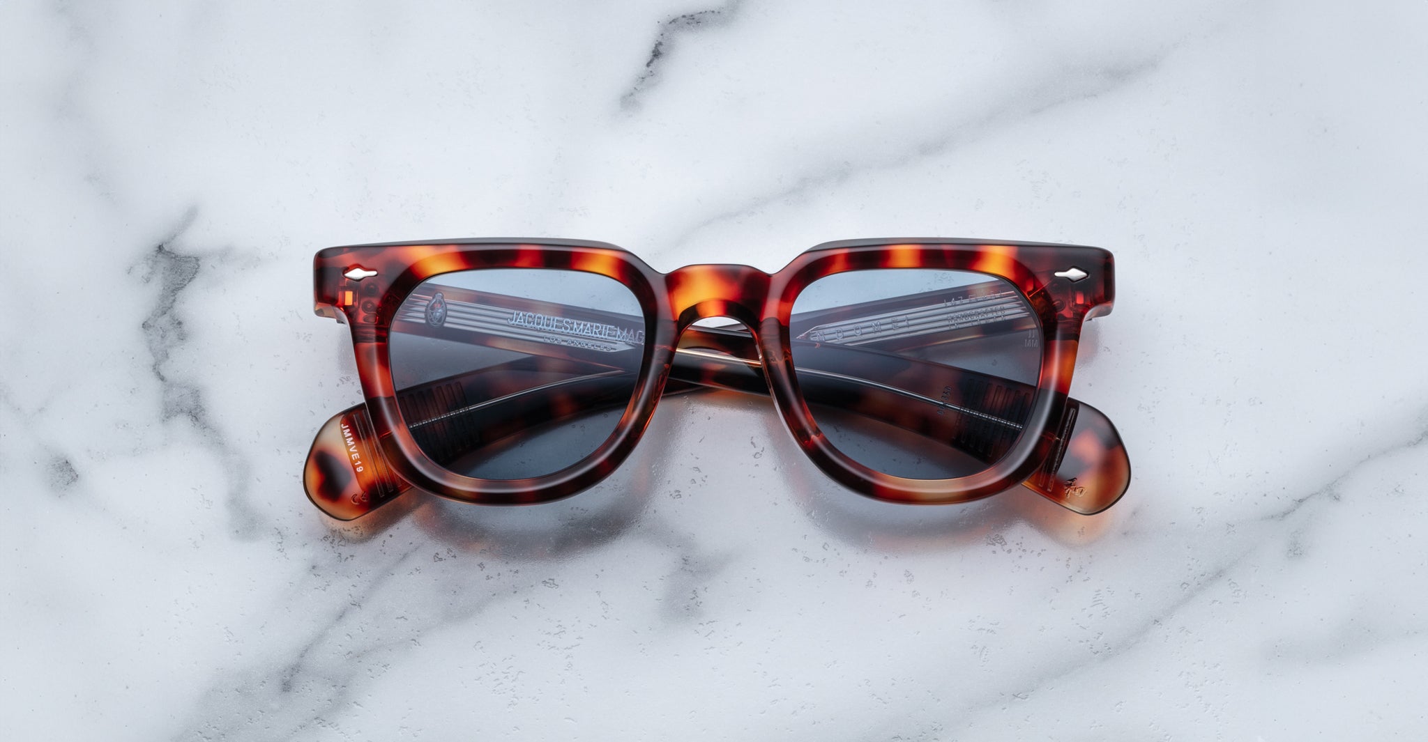 Jacques Marie Mage Vendome tortoiseshell sunglasses with dark lenses by Jacques Marie Mage, handcrafted in Japan, displayed on a white marble surface.