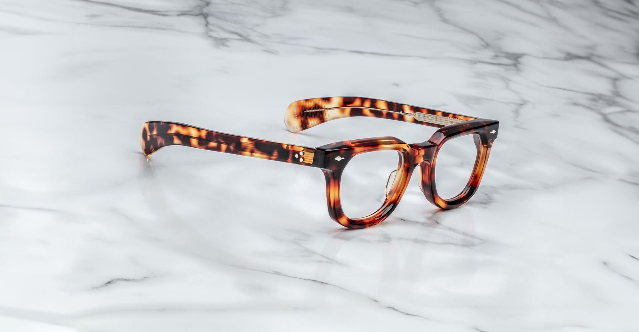 A pair of Jacques Marie Mage Vendome optical frames from Jacques Marie Mage, featuring a thick tortoiseshell design handcrafted in Japan, rests on a white marble surface.