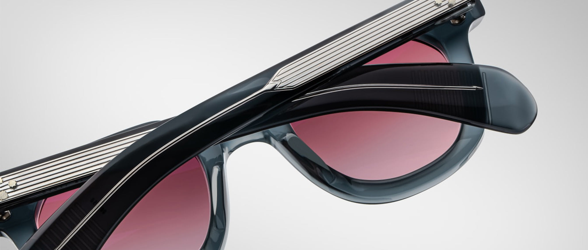 Close-up of Jacques Marie Mage Vendome sunglasses featuring dark frames, pink lenses, and metallic accents on the arms.