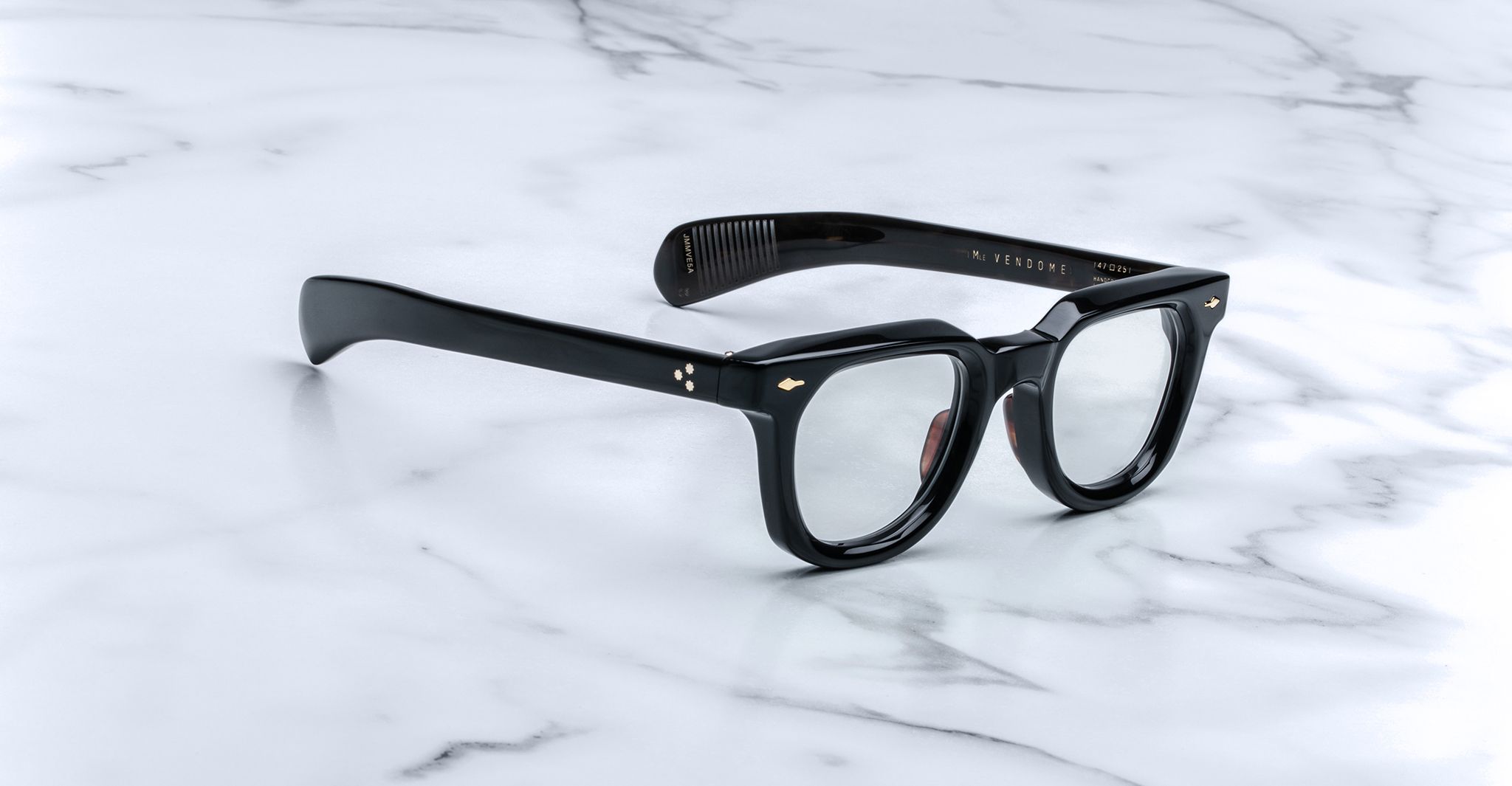 Jacques Marie Mage Vendome by Jacques Marie Mage: black thick-rimmed optical frames with clear lenses, handcrafted in Japan, displayed on a white marble surface.