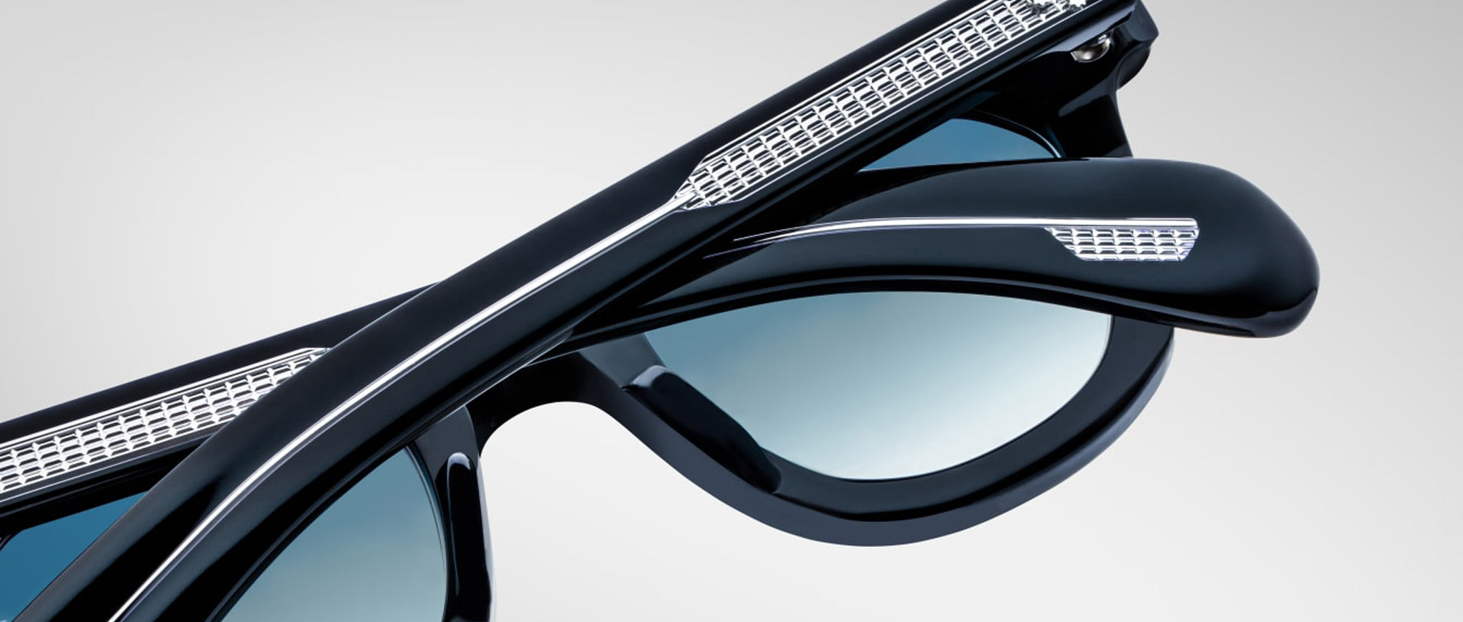 Close-up of two Jacques Marie Mage Vendome sunglasses showing blue-tinted lenses and metallic accents at the temples.