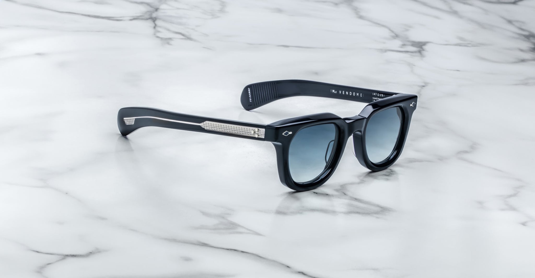 Jacques Marie Mage Vendome sunglasses by Jacques Marie Mage, handcrafted in Japan with blue lenses and silver-accented temples, shown on a white marble surface.