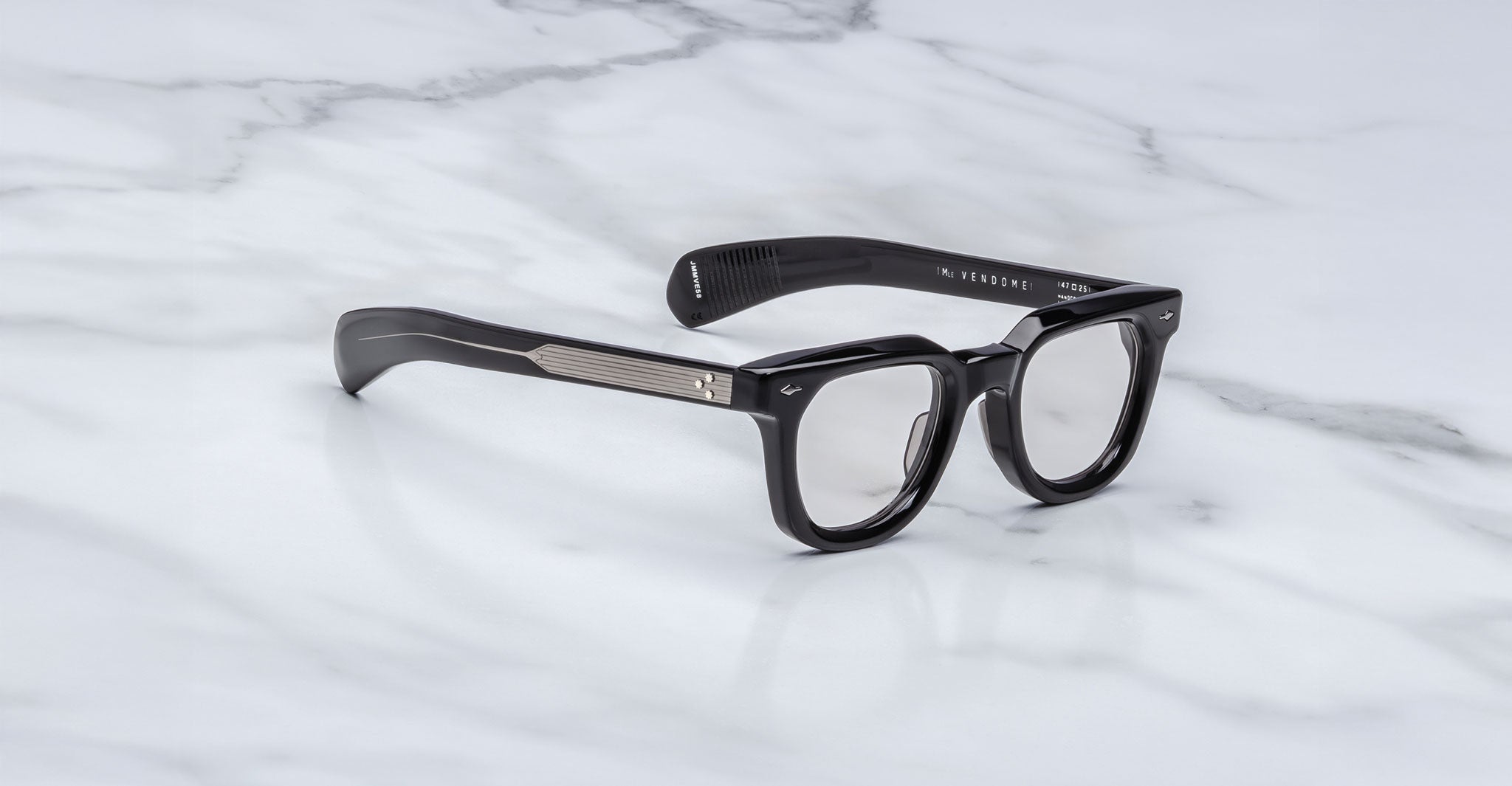 Jacques Marie Mage Vendome by Jacques Marie Mage: black rectangular optical frames with thick silhouettes and silver temple accents, handcrafted in Japan, displayed on a white marble surface.