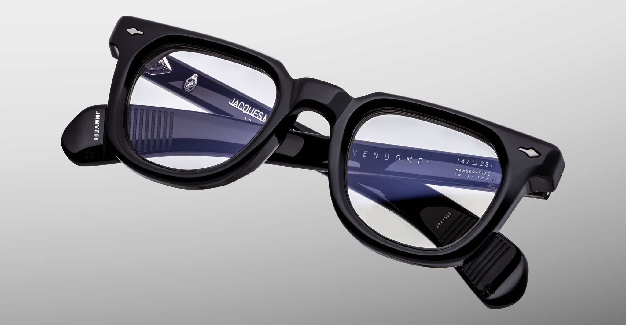 A pair of Jacques Marie Mage Vendome black rectangular optical frames with clear lenses, handcrafted in Japan and featuring branding and model info on the inner arm, is shown against a light gray background.