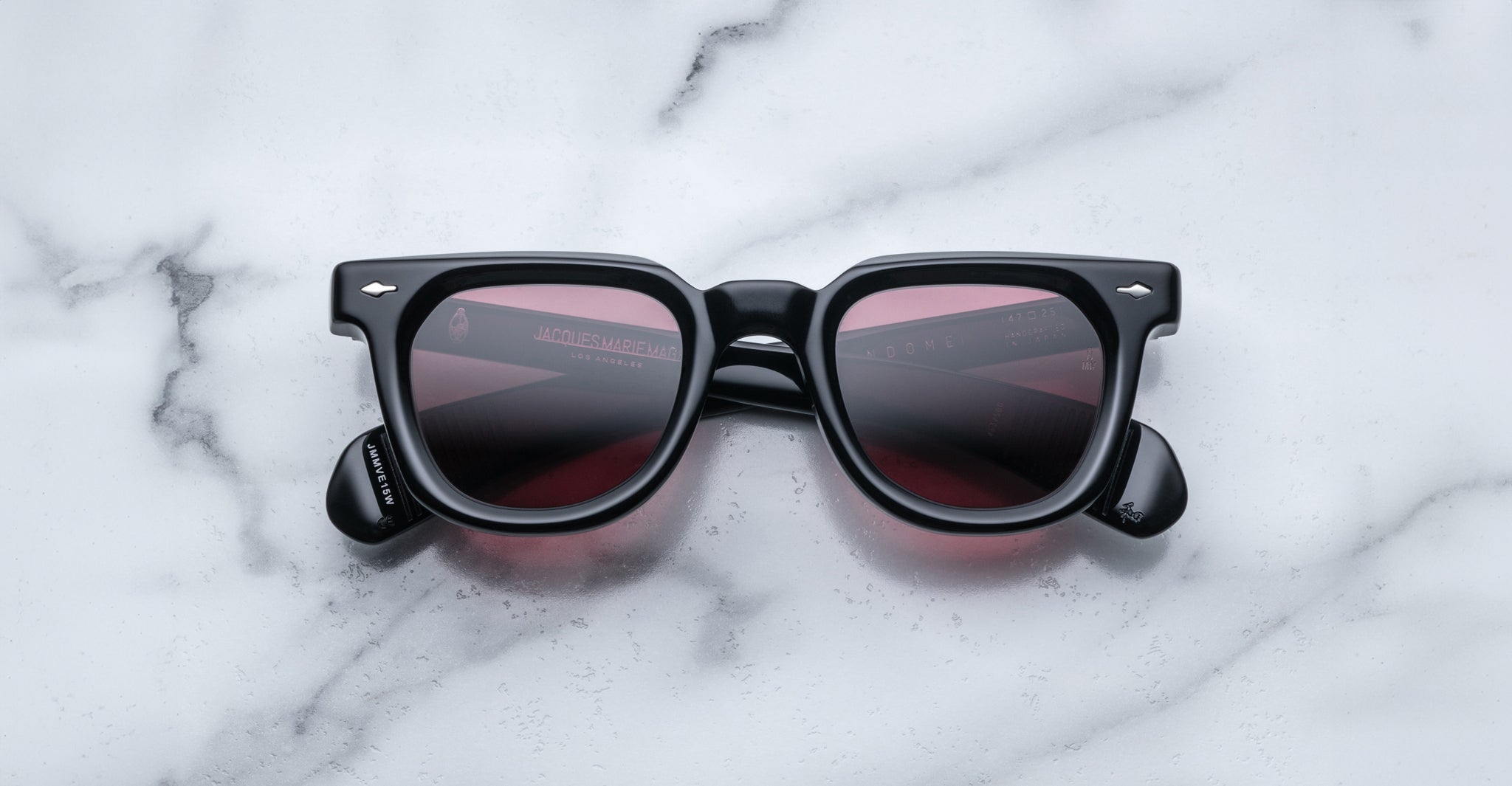 Jacques Marie Mage Vendome sunglasses by Jacques Marie Mage feature black frames and dark tinted lenses, handcrafted in Japan and displayed on a white marble surface.