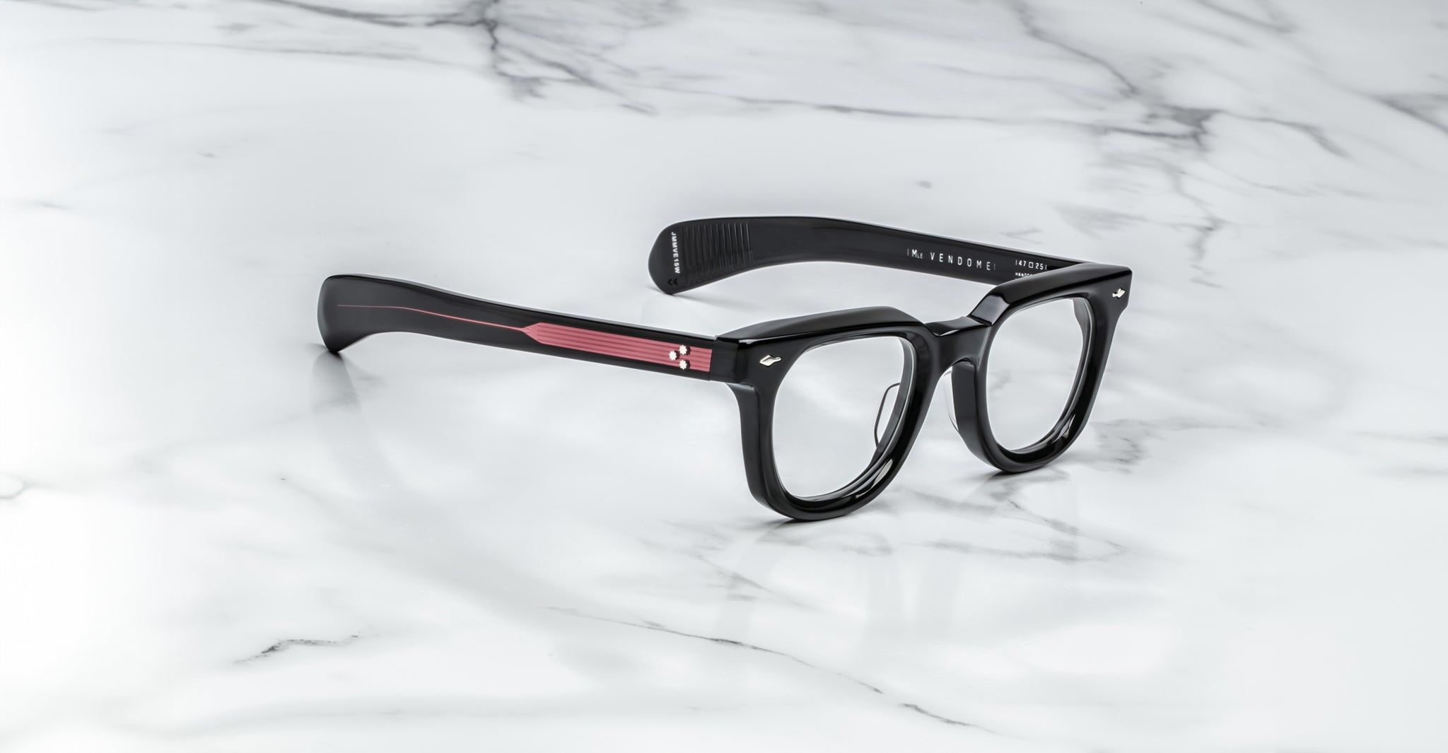 Jacques Marie Mage Vendome optical frames with bold edges and vivid red temples, handcrafted in Japan by Jacques Marie Mage, displayed on a white marble surface.