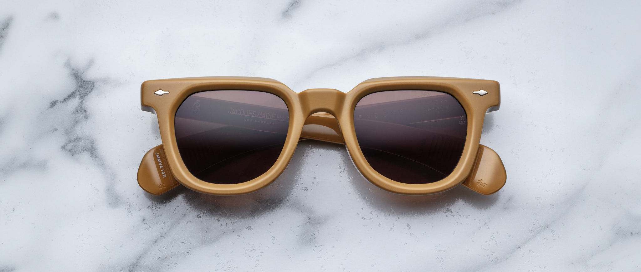 Jacques Marie Mage Vendome tan square sunglasses with dark lenses, viewed from above.