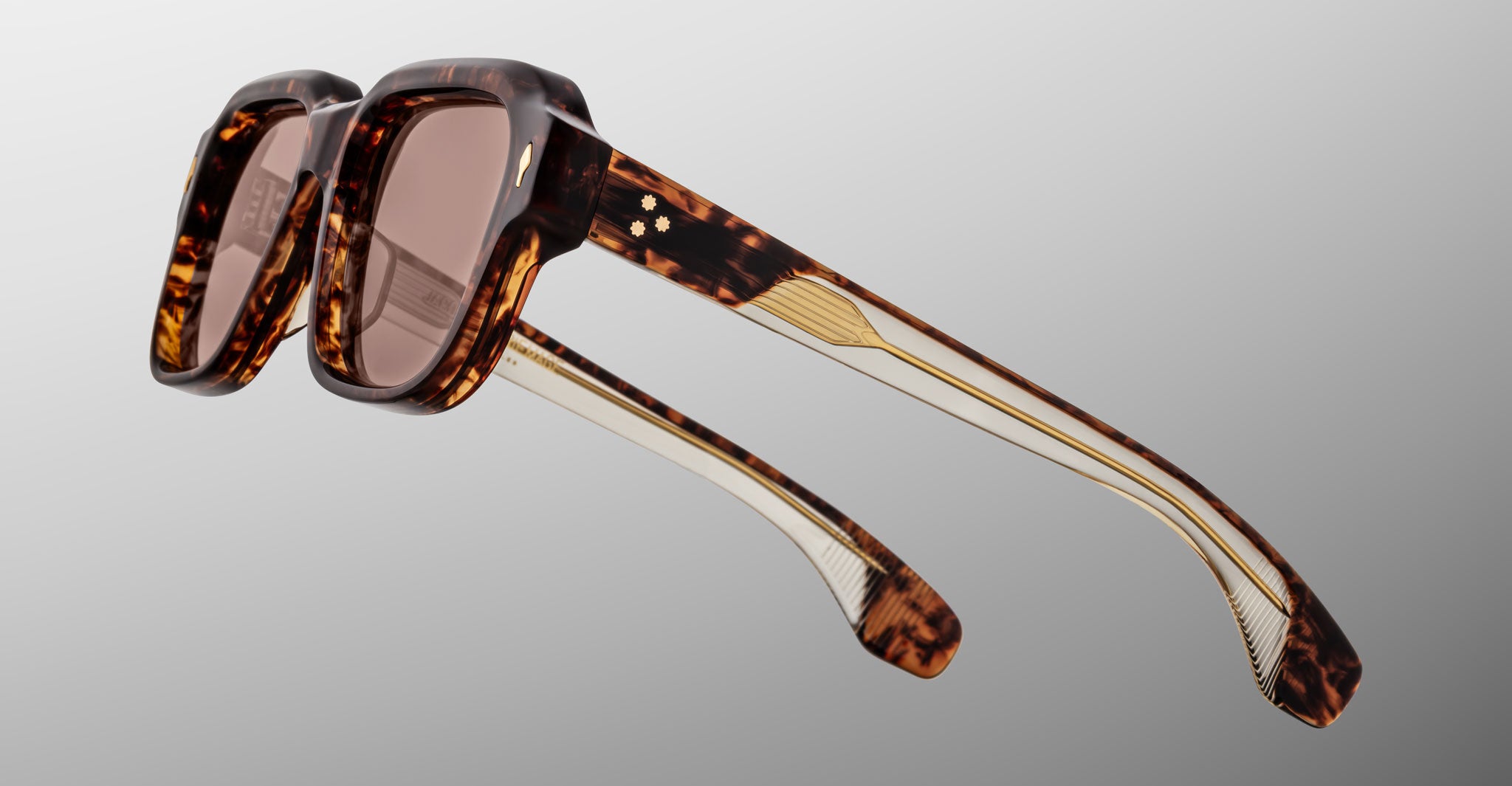 Tortoiseshell square sunglasses with brown tinted lenses and gold metal detailing on the arms, shown against a neutral gray background.