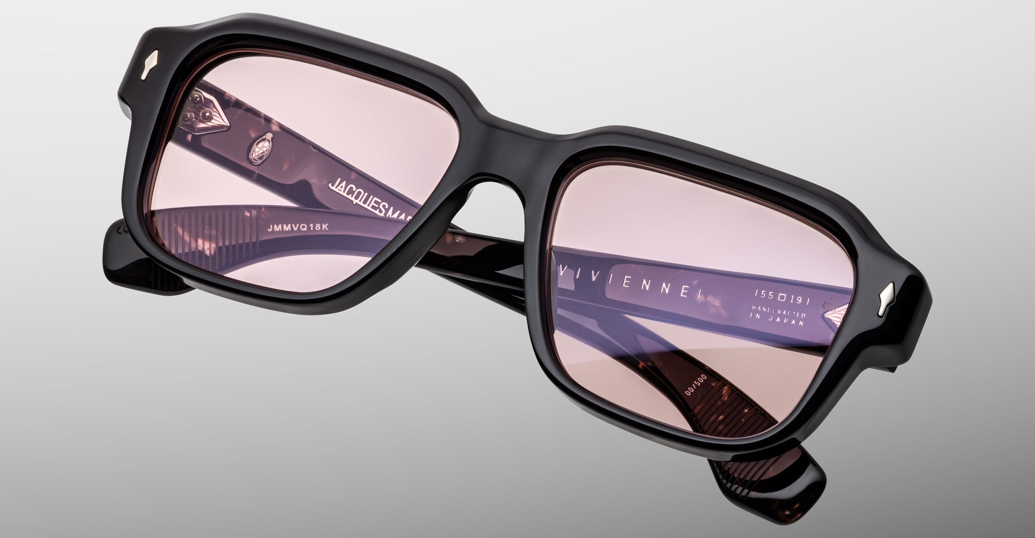 Black-framed square eyeglasses with light pink lenses are displayed on a gray background, featuring the Jacques Marie Mage Vivienne branding on the temple.