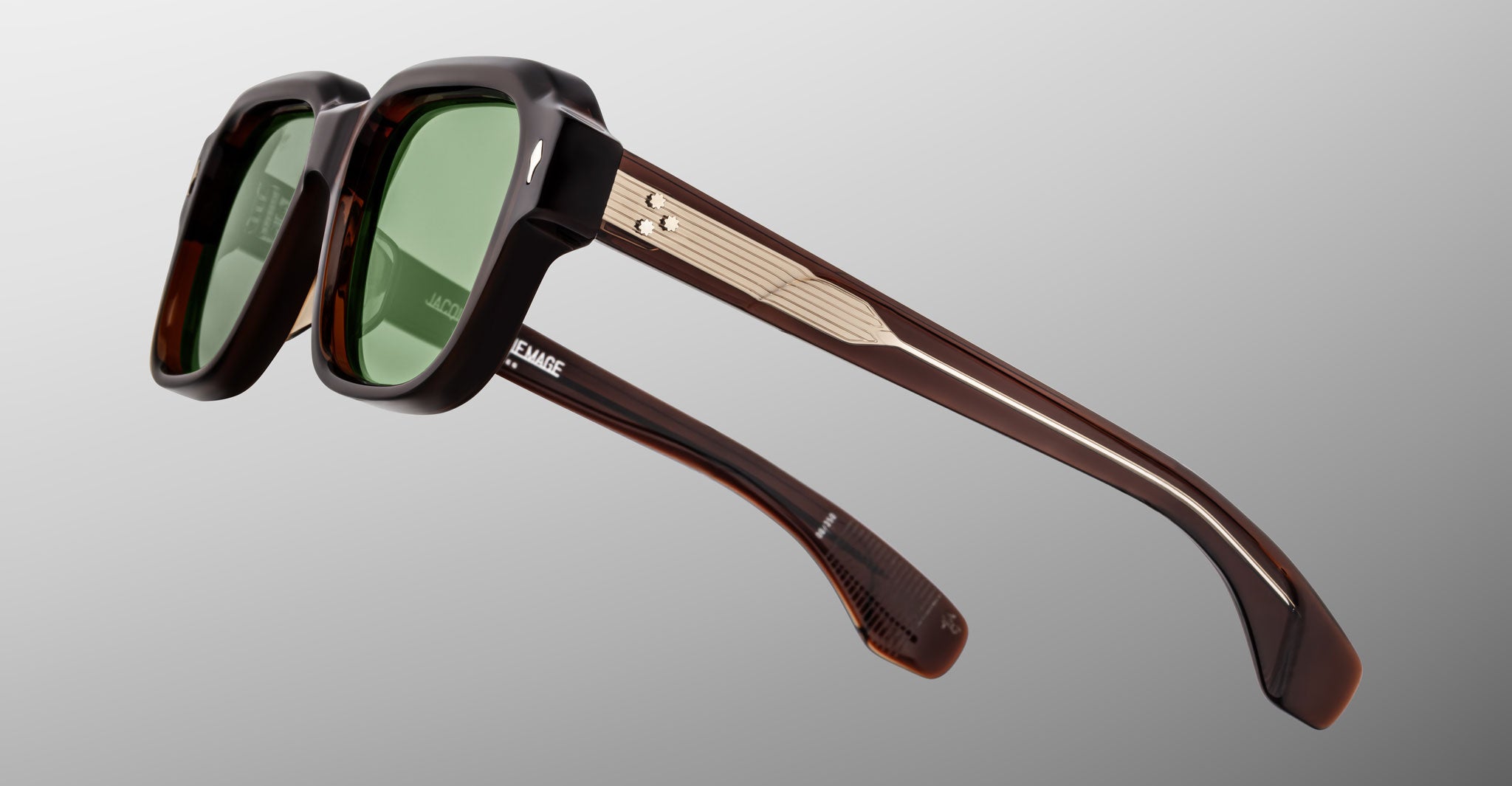 The Jacques Marie Mage Vivienne features stylish rectangular black frames, green lenses, and thick brown arms with metallic accents, displayed on a light gray background.