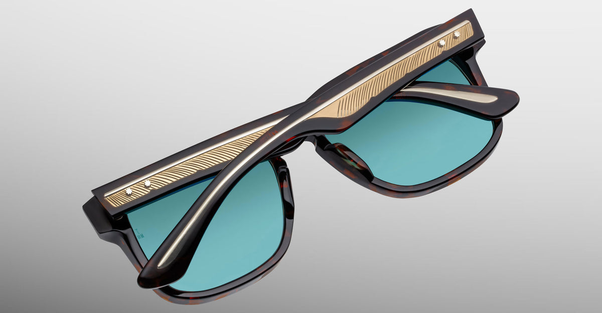 Jacques Marie Mage Wesley sunglasses with teal lenses, black-brown frames, gold bar; front view.