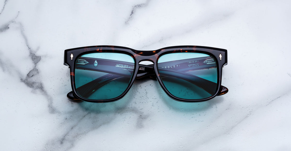Jacques Marie Mage Wesley sunglasses with blue lenses and rounded arms, shown from above.