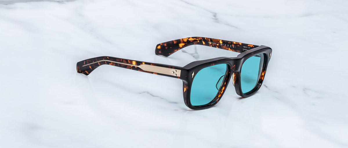 Jacques Marie Mage Yves sunglasses with teal lenses, viewed from above, displayed on a flat surface.