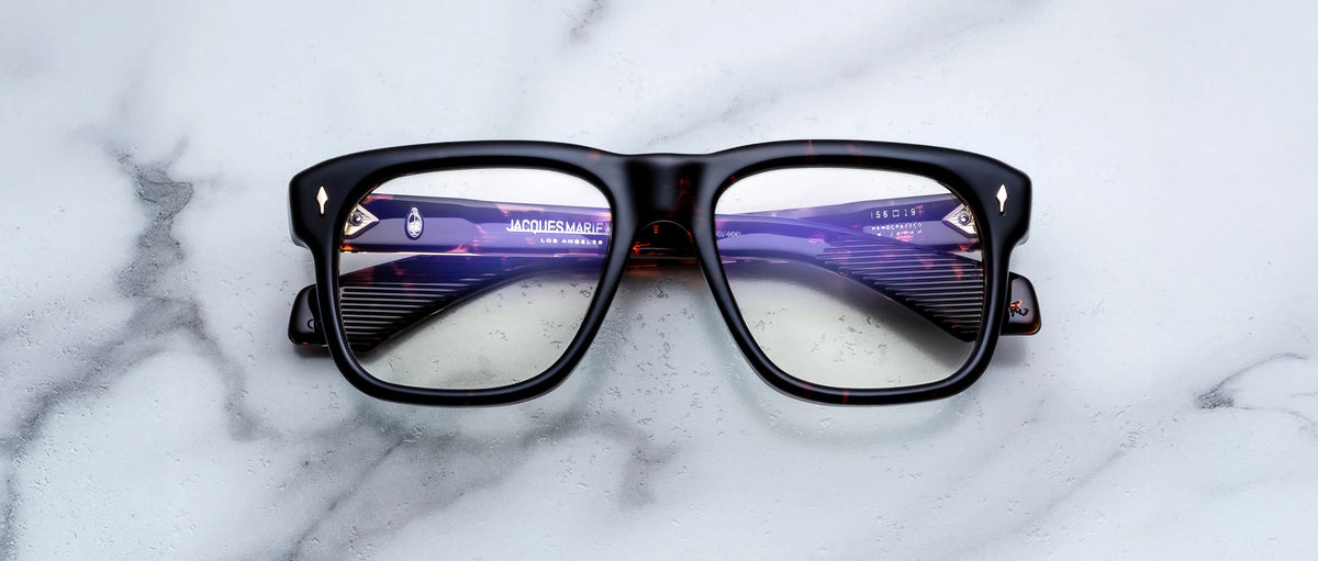 Jacques Marie Mage Yves black eyeglasses, front view, with subtle reflections on lenses.
