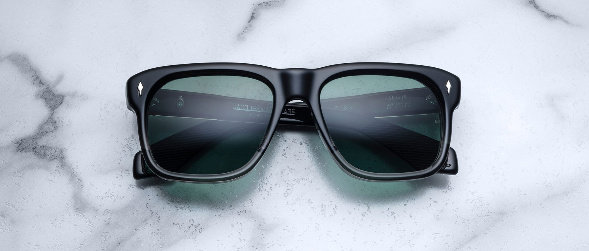Jacques Marie Mage Yves black rectangular sunglasses with green lenses, shown from above.