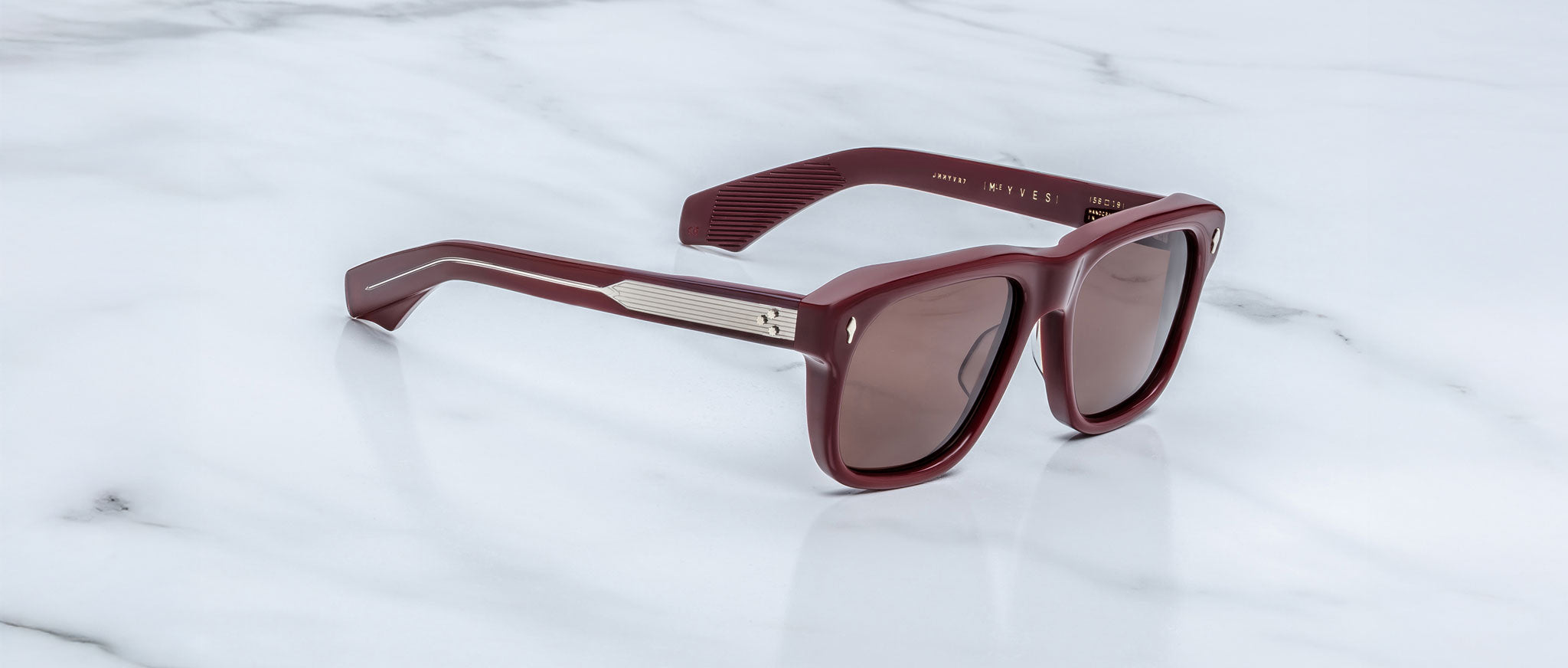 Jacques Marie Mage Yves in Bordeaux Empire sunglasses, rectangular deep red acetate frame with rose-tinted lenses, signature arrowhead rivets, and exposed engraved metal core temples, angled side view