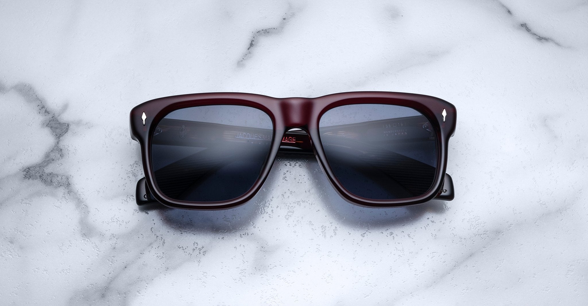 Jacques Marie Mage Yves sunglasses with square maroon frames and dark lenses, front view.