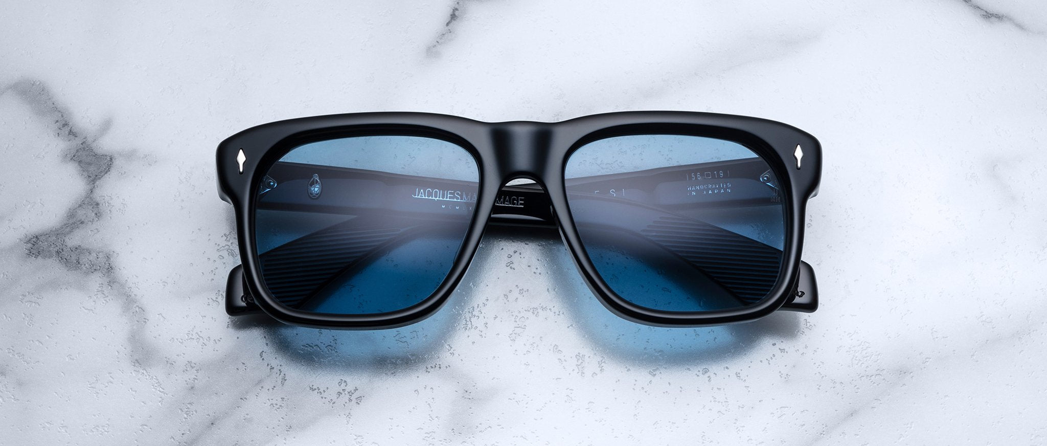 Jacques Marie Mage Yves sunglasses, black square frames with blue-tinted lenses, front view.