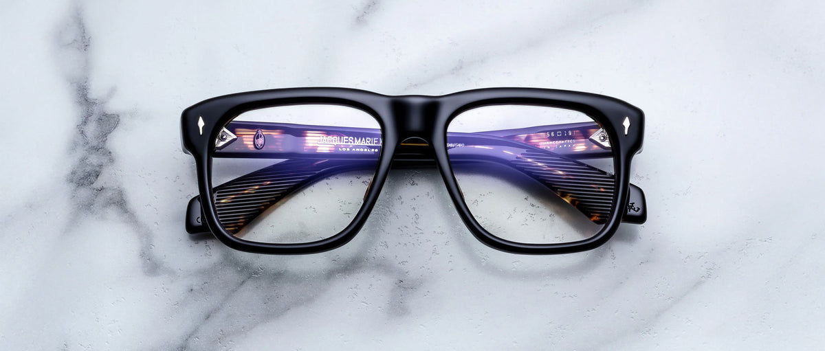 Jacques Marie Mage Yves black eyeglasses with thick frames, front view showing lens reflections.