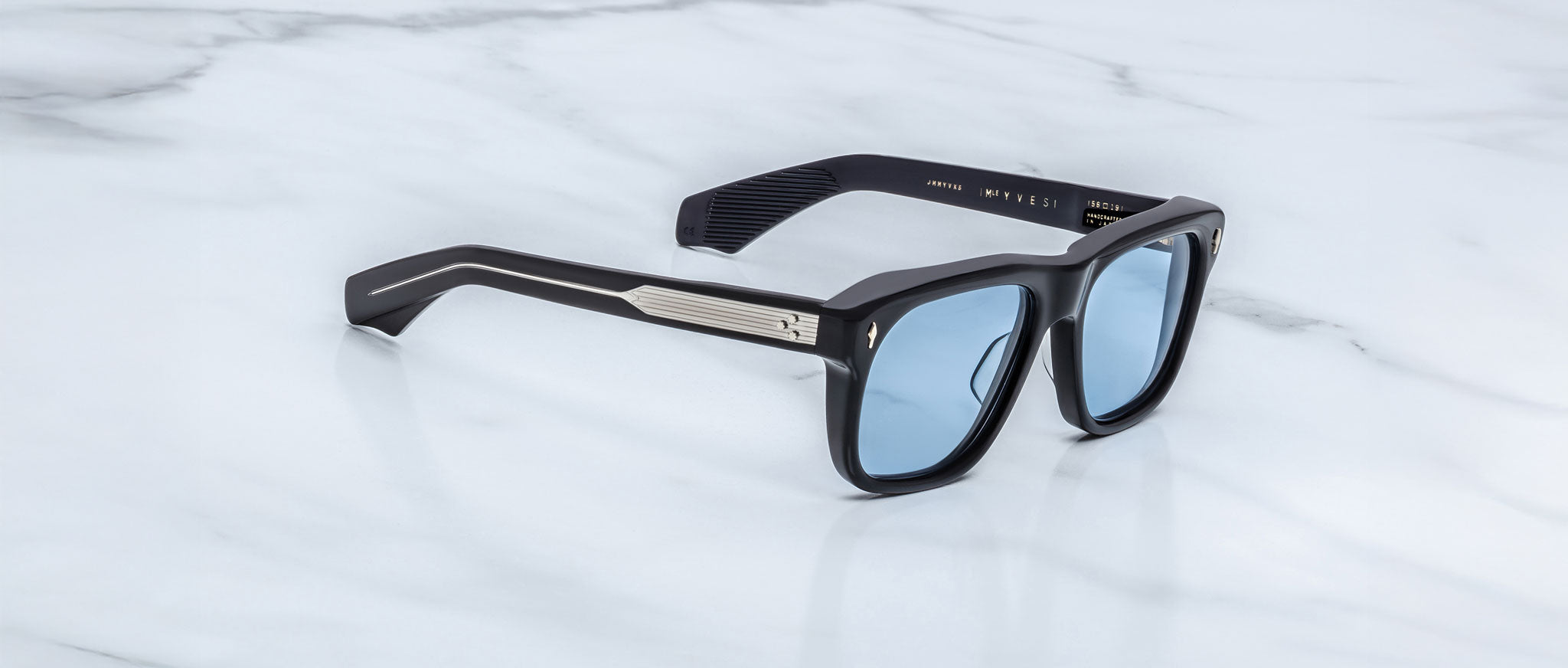 Jacques Marie Mage Yves in Obscure Black sunglasses, rectangular matte black acetate frame with blue-tinted lenses, signature arrowhead rivets, and engraved metal core temples, angled side view