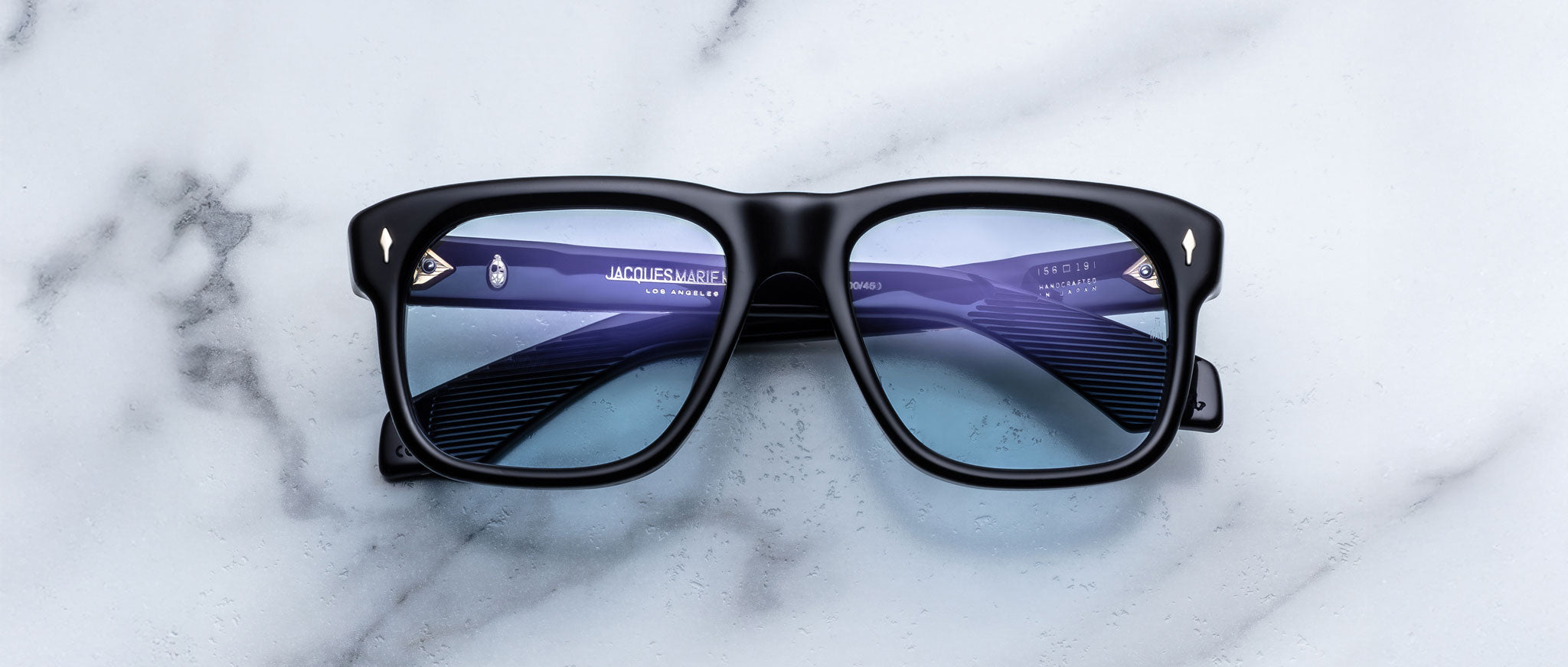 Jacques Marie Mage Yves in Obscure Black sunglasses, rectangular matte black acetate frame with blue-tinted lenses and signature arrowhead rivets, front view