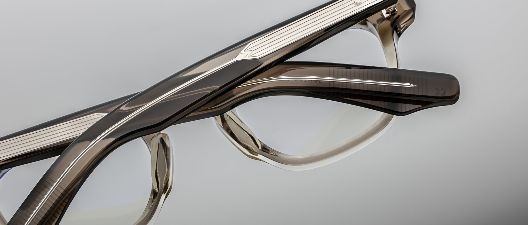Close-up of two Jacques Marie Mage Zephirin 47 eyeglasses in translucent brown and clear frames, side-by-side, top view.
