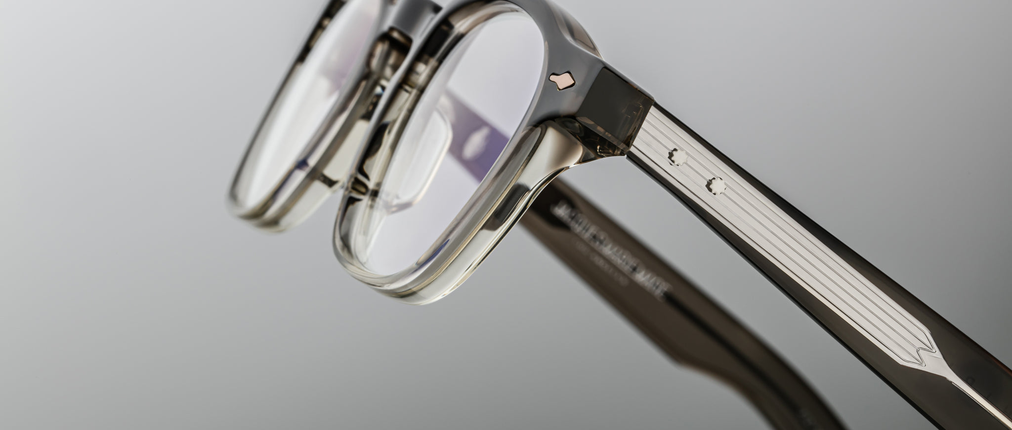 Close-up of Jacques Marie Mage Zephirin 47 eyeglasses, clear frame, silver temple accents, front and side details visible.