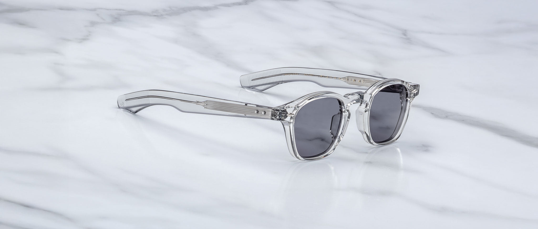 Jacques Marie Mage Zephirin 47 clear-framed sunglasses with dark lenses, front angled view.