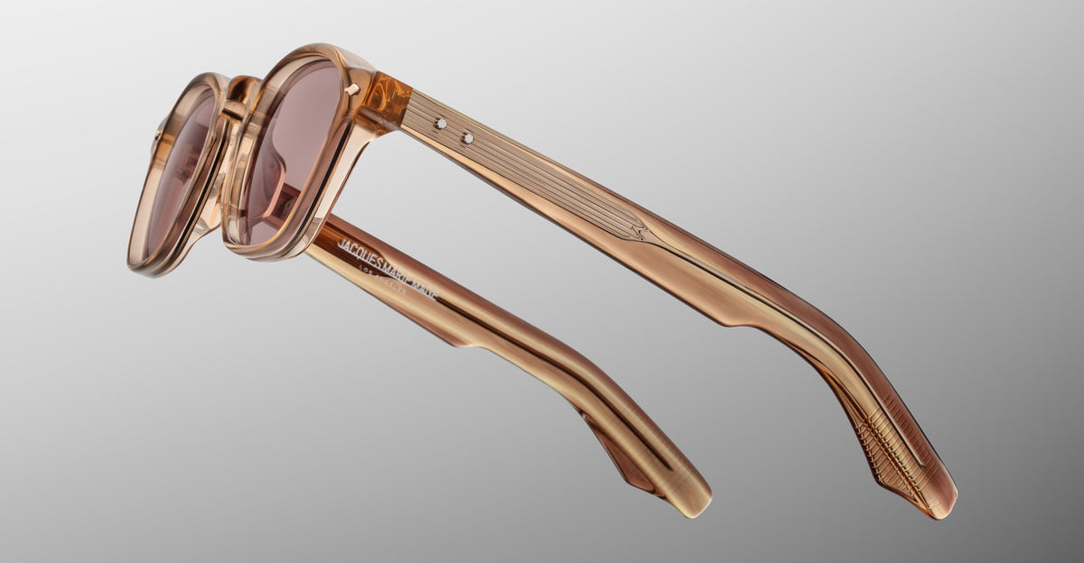 Jacques Marie Mage Zephirin sunglasses in Casliza, side detail showing translucent amber acetate temples, rose-tinted lenses, and gold-tone hardware.