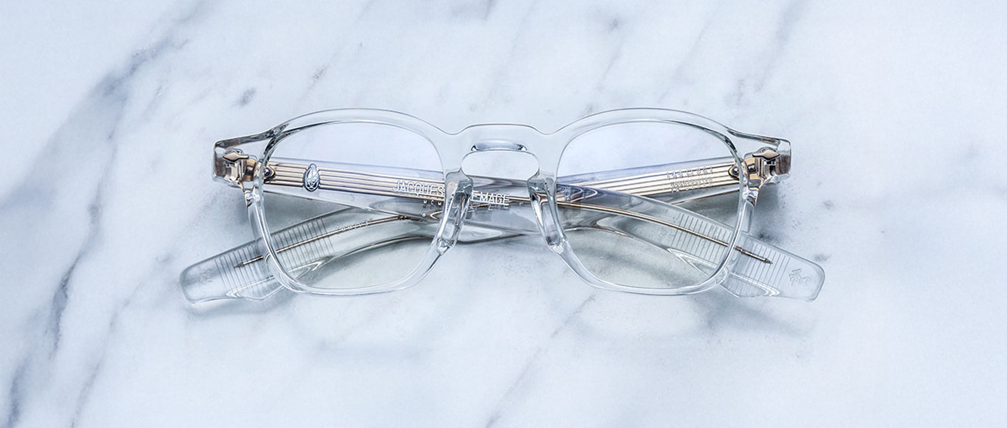 Jacques Marie Mage Zephirin clear eyeglasses with silver accents, crossed arms, top view.