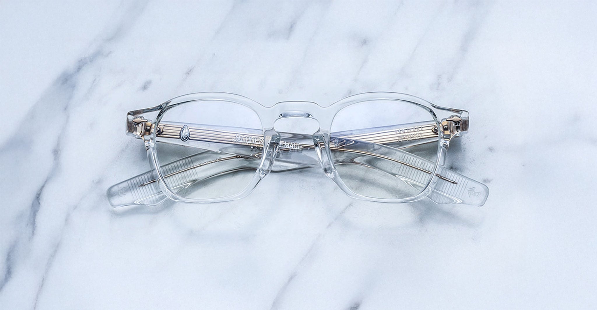 Jacques Marie Mage Zephirin clear eyeglasses with silver accents, crossed arms, top view.
