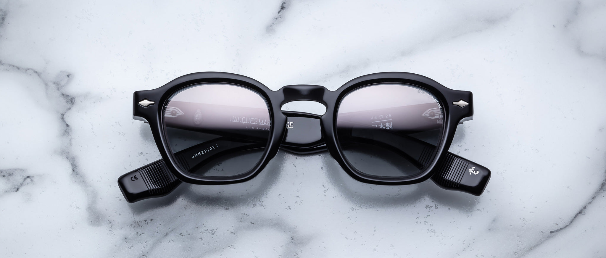 Jacques Marie Mage Zephirin black round sunglasses with thick frames are displayed on a white marble surface.