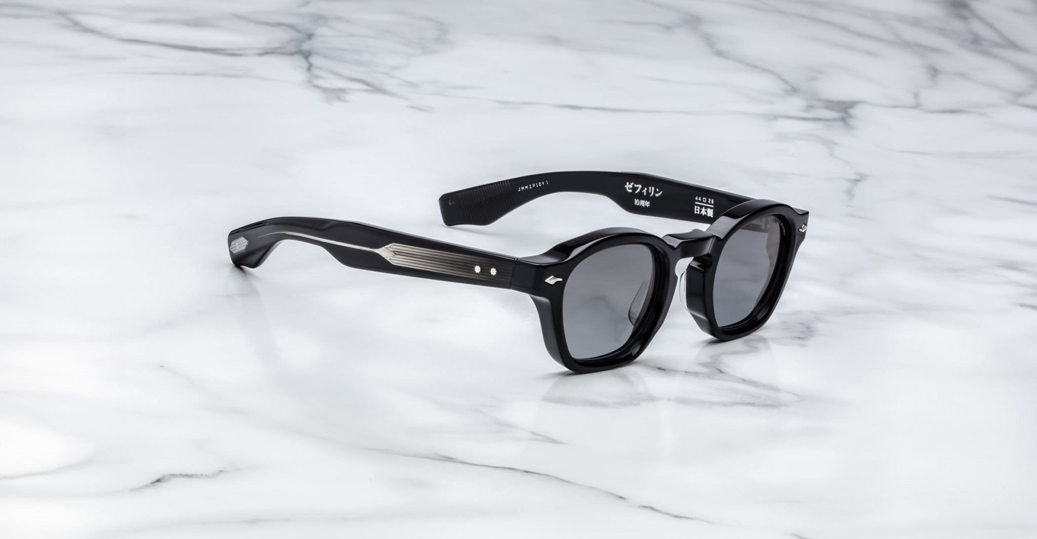 The Jacques Marie Mage Zephirin sunglasses by Jacques Marie Mage feature black round frames with silver temple accents, inspired by limited edition eyewear, displayed on a white marble surface.