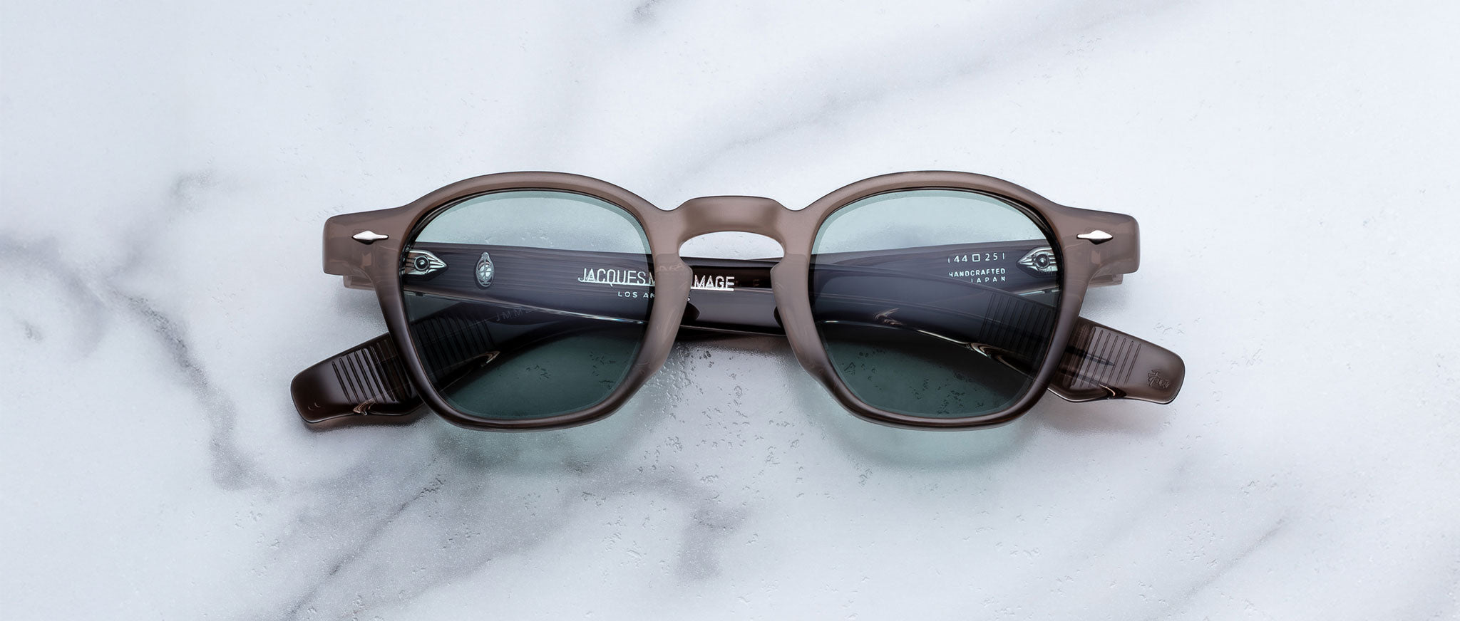 Jacques Marie Mage Zephirin in Dusty Jade round, dark-framed sunglasses with tinted lenses, front view on a flat surface.